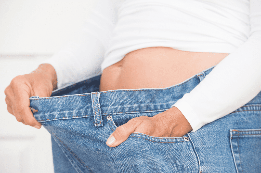 person showing weight loss on waist, jeans are too big