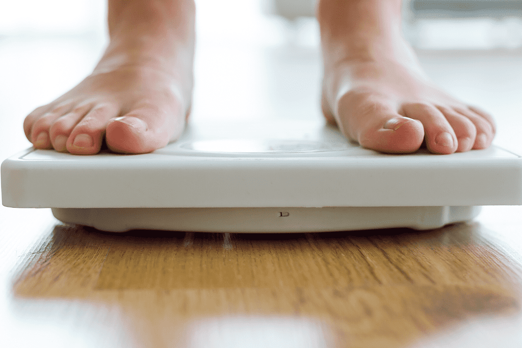 person standing on scale weighing themselves for permanent weight loss