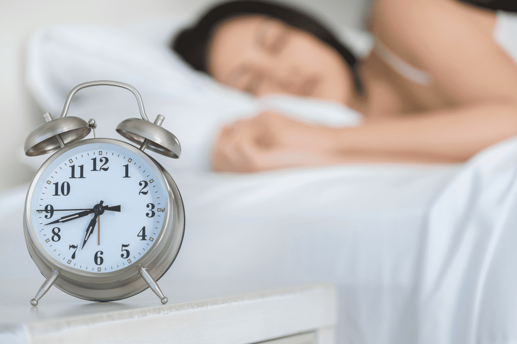 woman sleeping with an alarm clock in the forefront