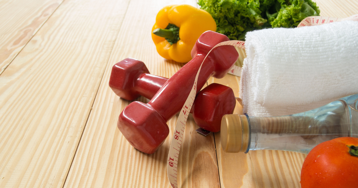 healthy lifestyle items - dumbbells, towel, vegetables